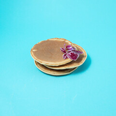 American pancakes decorated with a flower on a blue background. Creative food concept.