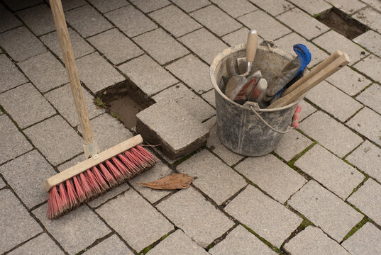 Small repairs to a paved path bucket with tools and broom from a bird's eye view