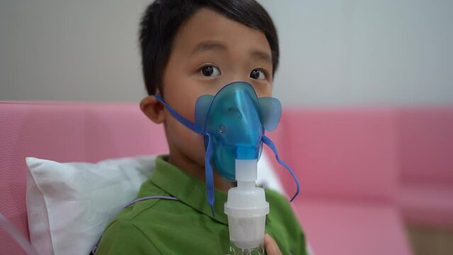 Little boy making inhalation with nebulizer at home.