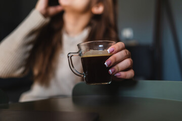 A young girl sitting at home while using laptop to study or do business while drinking coffee and using mobile phone