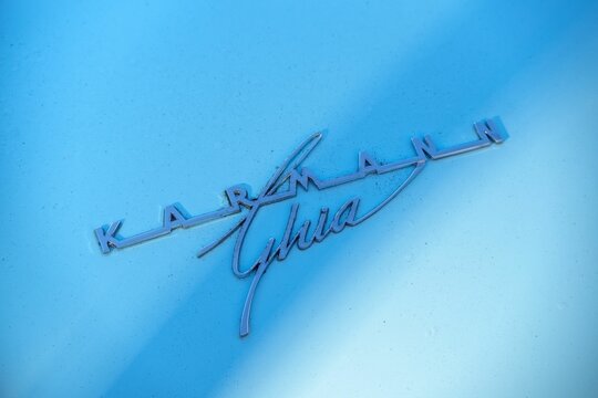 Chrome emblem of blue VW Karmann Ghia vintage coupe car.