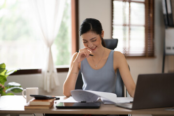 Young Asian businesswoman reading graphs and talking on phone with customers in office