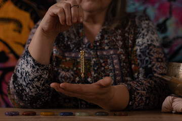 Elderly white-haired woman holding a pendulum in a divination session