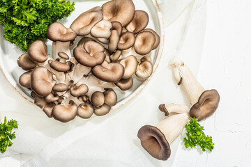 Fresh oyster mushrooms on a ceramic plate with parsley. Healthy ingredient for cooking vegan food