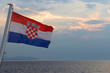 Flag of Croatia on the boat, blowing in the wind. Sea and sunset sky in the background. Selective...
