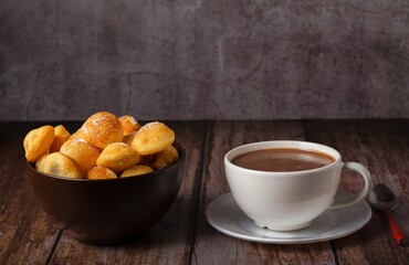 homemade doughnuts with sugar in a bowl and hot chocolate in a white mug