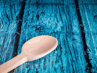 A hand made craft wooden spoon in the kitchen. Isolated spoon on blue background.