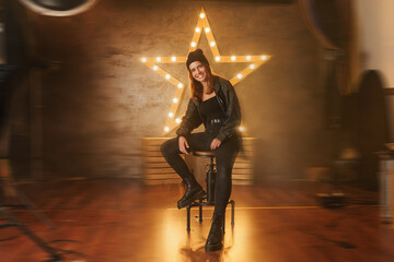 Young beautiful smiling star female in trendy leather jacket on stage. Be a star Photo Shoot...