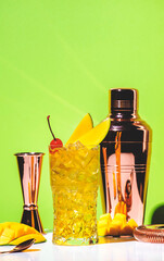 Mango rum collins alcoholic cocktail drink with white rum, syrup, ginger beer, lemon juice, ice and mango. Green background,  copy space