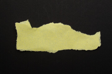 Recycled yellow paper on a black background. Torn paper background with copy space for text.