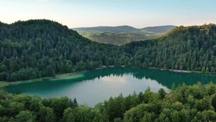 Sunset fly over mountain lake Alatsee. Wild nature and pine forest.