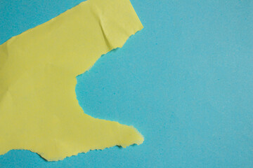 Crumpled yellow paper on a blue background. Wrinkled torn paper background.
