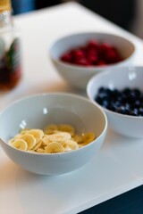 Vertical shot of three bowls with fresh bananas and other berries on a table