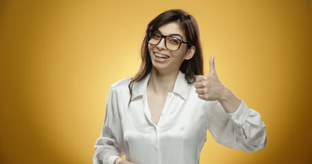 Happy south asian woman in glasses getting surprised and cheering, expressing positive emotions, isolated on yellow background close up. A template for your graphics. Copy space