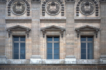 Fototapeta na wymiar Paris ancient stone building facade with three French windows and rich stucco fretwork.