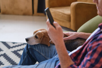 Stay connected while spending quality time with your furry friend: a man enjoys scrolling through his phone while his Beagle snuggles up next to him on the couch.