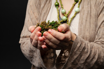 Naklejka na ściany i meble Close-up of a female druid or shaman hands holding magical herbs or plants on a black isolated background. Nature spirituality ,Shamanism, Herbalism, Ritual practice, Mythic symbolism.