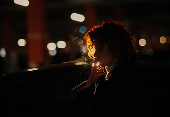 Silhouette of young woman smoking cigarette