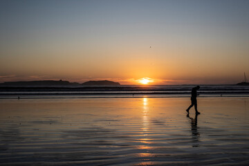 Fototapeta premium Man walking at sunset on the beach