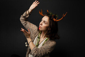 A portrait of a female druid or shaman with horns, holding ritual talismans in her hands on a black isolated background.Shamanic practices,Spiritual rituals,Pagan beliefs,Nature worship,Mystical.