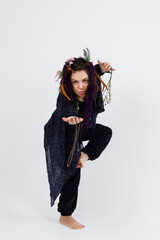 A female druid or shaman in black robe and with horns, holding ritual talismans in her hands on a white isolated background. Shamanic practices,Spiritual rituals,Pagan beliefs,Nature worship,Mystical.