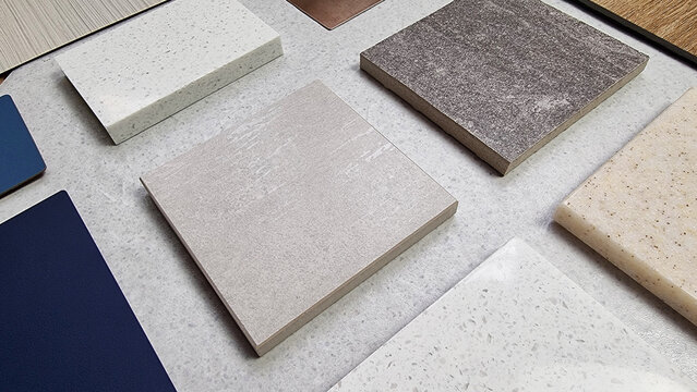 samples of interior stone material consists travertine tile, rustic concrete tile, grainy artificial stones, quartz with blue laminated, close up view (focused at center of image).