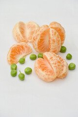closeup the bunch ripe sliced orange fruit with green peas on the white background.