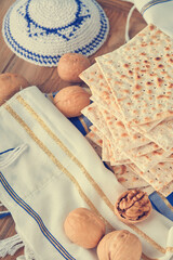 Passover celebration concept. Matzah, red kosher and walnut. Traditional ritual Jewish bread matzah, kippah and tallit on old wooden background. Passover food. Pesach Jewish holiday. Toned image.