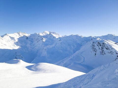 Panoramic view of French alpine rugged peaks covered with snow, with ski slopes .