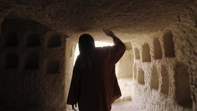 Camera follows happy tourist woman walking along ancient rock cave building hall touching ceiling in Cappadocia Turkey.