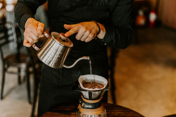 Professional barista preparing coffee using chemex pour over coffee maker and drip kettle