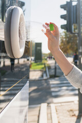 Woman uses a self service machine to receive used plastic bottles and cans on a city street	