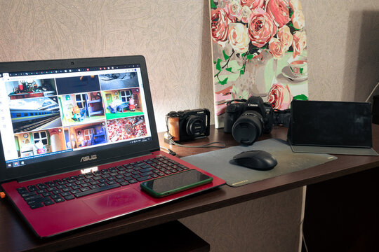 Desktop with a red Asus laptop and two Canon cameras