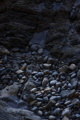 rocks on the beach with a creek path cold and wet day on coast