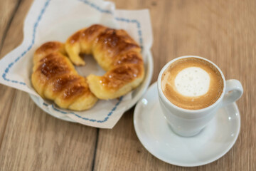 cafetería café cortado expreso con 2 medialunas  sobre mesa de madera 
