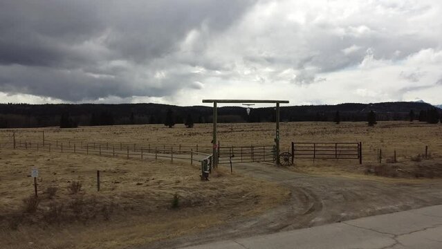 Rustic gated entrance to a ranch overlooking brown fields