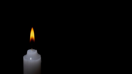 white burning candle on a black background	