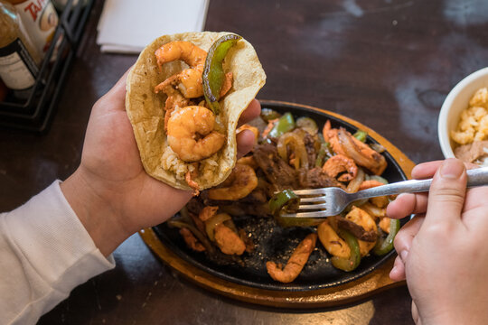 Restaraunt patron making a shrimp fajita at a traditional mexican restaraunt