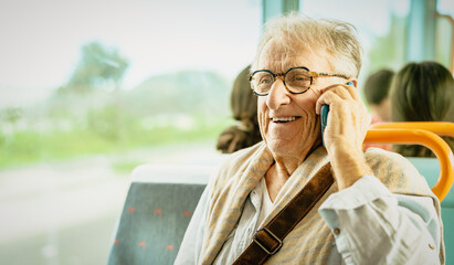 Happy senior man having a call with smartphone while traveling by bus