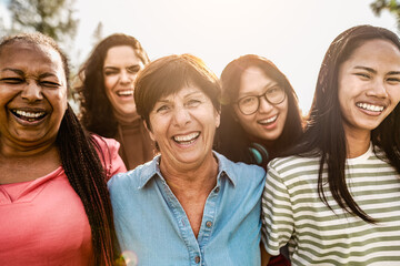 Happy multigenerational women with different ethnicity having fun smiling in front of camera in a public park - Females empowerment concept
