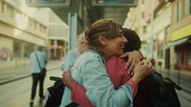 Happy multiracial women hugging while waiting at the bus station