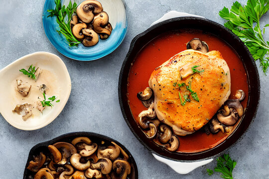 Baked chicken with mushrooms. In a black square dish, on a black table