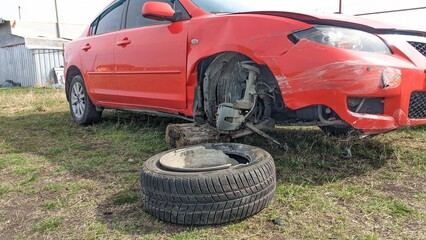 A car after a traffic accident, a broken headlight, a torn wheel, a broken car wing