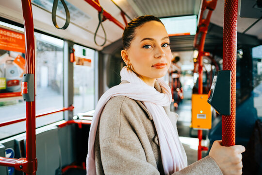 An attractive caucasian woman riding in a bus in the sunny day. Young beautiful woman using public transportation.