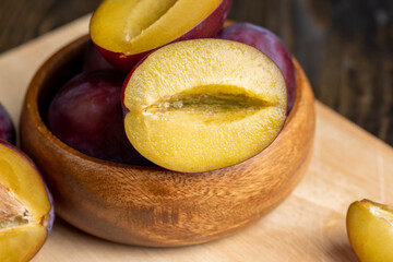Ripe dark - colored plums sliced on the table