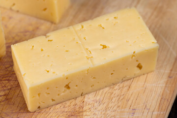 Hard cheese with holes cut into thick pieces on a cutting board