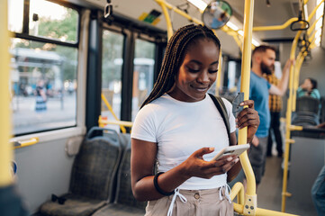 African american woman riding in a bus and using a smartphone
