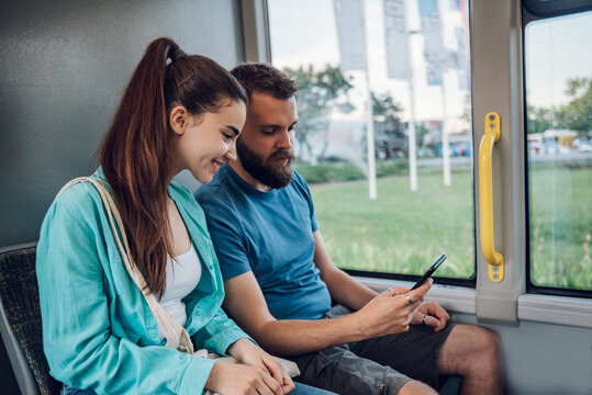 Friends talking and using a smartphone while riding a bus in the city - Powered by Adobe