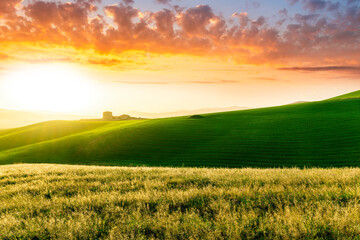 Fototapeta premium beautiful sunset or sunrise in rural countryside green hills with farm and mountains on background
