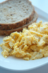 morning breakfast with Scrambled eggs on a bread on white plate 